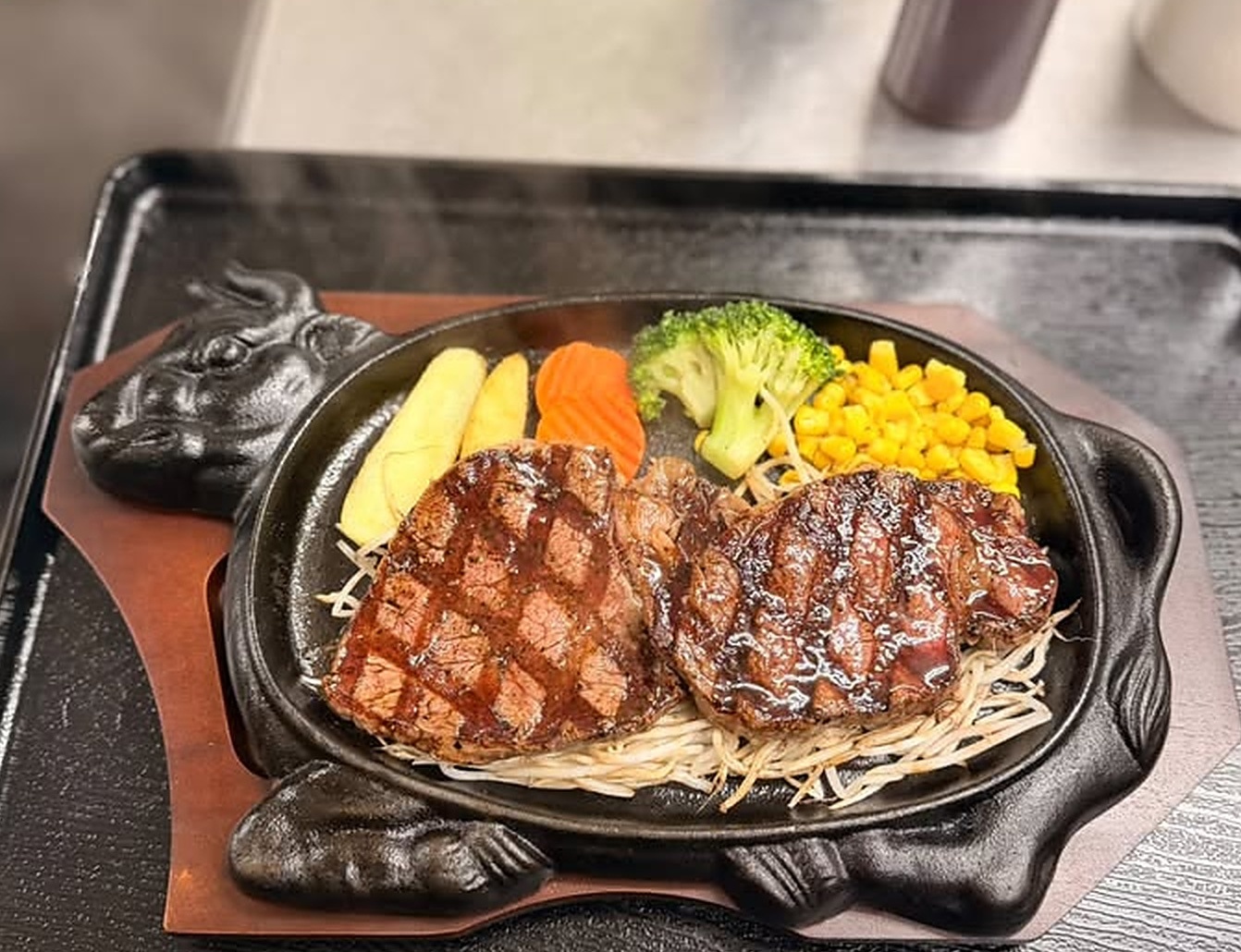牛型鉄板に盛り付けたステーキの提供写真